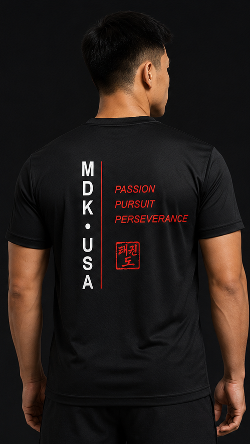 Person wearing a black t-shirt with text and symbols on the back, standing against a black background.